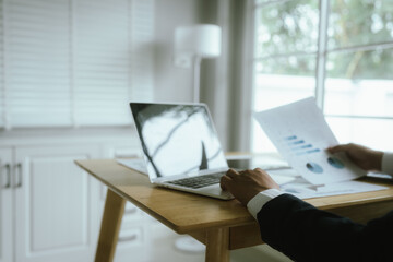 Focused professional analyzes financial documents and growth charts at office desk, planning investment strategy and business development for company success.