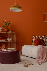 Cosy corner with orange armchair, decorative shelving, and rounded pendant lamp. Stylish home decor.