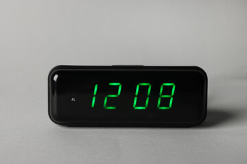 Digital alarm clock showing 12:08 o'clock on grey background