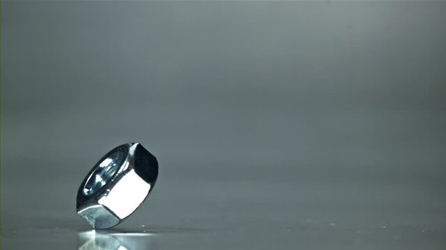 The nut is spinning on a metal table. Filmed on a high-speed camera at 1000 fps. High quality FullHD footage