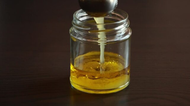 Close-up video of making salad dressing in a glass jar by mixing fresh ingredients.
