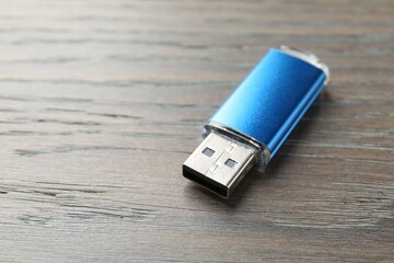 One flash drive on wooden background, closeup. Space for text