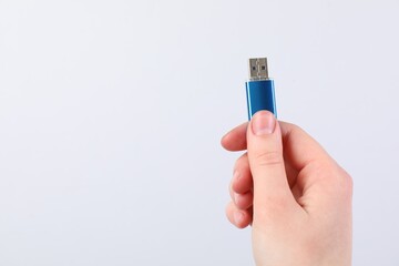 Man with modern flash drive on light grey background, closeup. Space for text