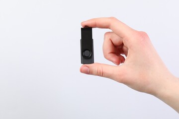 Man with modern flash drive on light grey background, closeup. Space for text