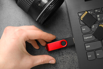 Man inserting modern flash drive at grey table, top view