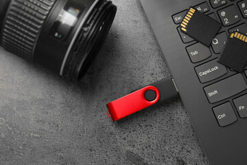 Flash drive, laptop, SD memory cards and camera on grey table, flat lay