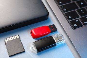 Flash drive, SD memory cards, external hard disk and laptop on light grey table, closeup