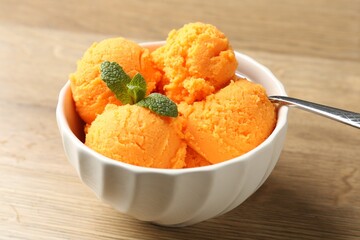 Tasty orange sorbet and mint on wooden table, closeup
