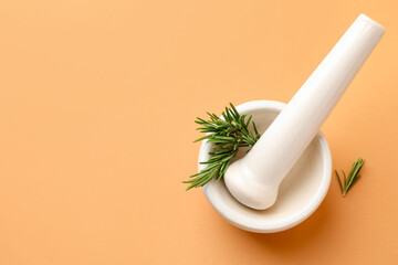 Ceramic mortar with rosemary and pestle on light brown background, top view. Space for text