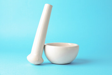Ceramic mortar and pestle on light blue background, closeup