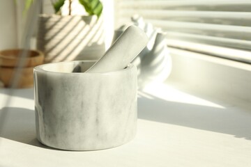 Marble mortar and pestle on windowsill indoors, closeup. Space for text