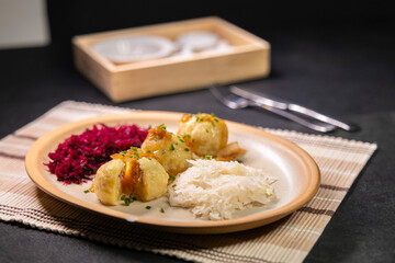 Potato dumplings filled with minced meat, topped with fried onions, served with sauerkraut and red cabbage