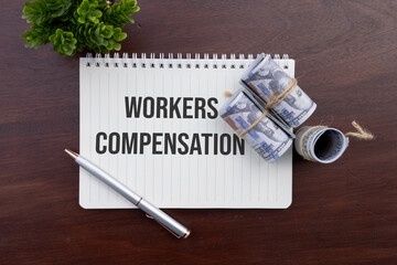 A financial notebook marked "Workers Compensation" with bundled cash resting nearby, indicating a compensation claim or payment process.