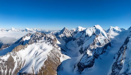 Obraz premium stunning aerial view of snow capped mountains under a clear blue sky showcasing nature s beauty and majesty