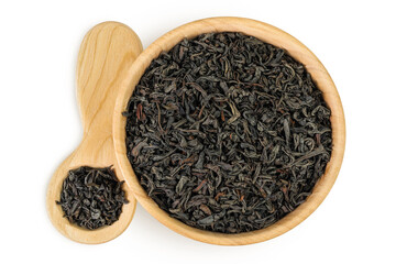 Dry black tea leaves in wooden bowl and spoon isolated on white background. Top view. Flat lay