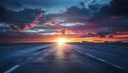 Empty asphalt road under dramatic sunrise/sunset sky with white markings.