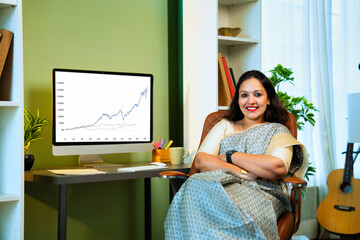 Indian lady in saree tracks share market at home, smiles at camera with confidence
