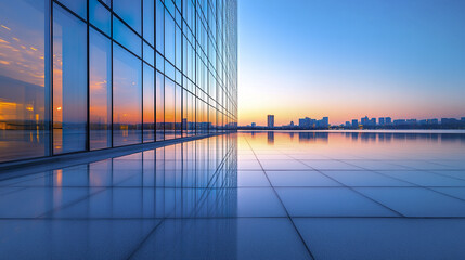 Obraz premium modern glass building reflecting on calm water at sunset, creating serene atmosphere