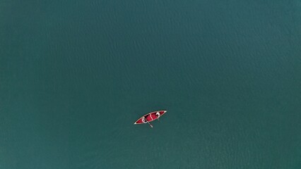 A young guy and a girl are sailing on a rowing boat on the lake. A couple on a canoe take a photo...