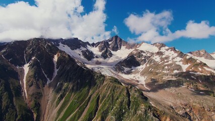 Steep rocky mountains with cliffs and ledges, covered with snow and clouds. Mount Elbrus, video filming from a quadcopter in the daylight