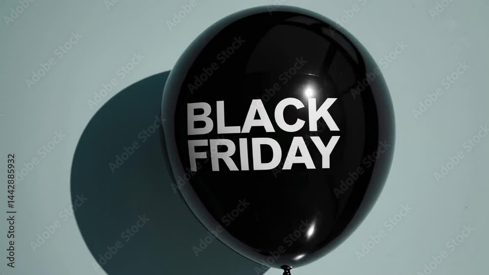 Poster Multiple black balloons with the words black friday printed on them float against a light blue background, creating a visual representation of the popular shopping event