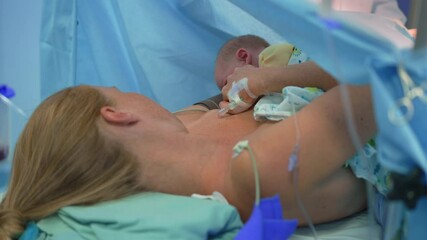 A just-born baby attempts breastfeeding for the first time while lying on the mother s chest as the surgeon completes the cesarean section. A tender moment of bonding, nourishment, and love during