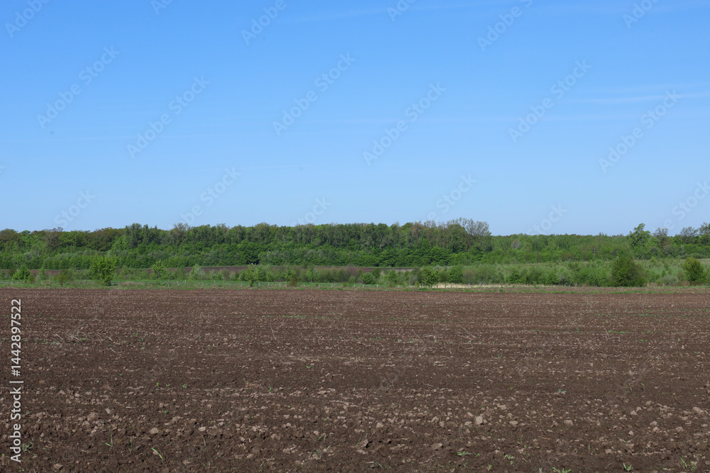 Leinwandbilder the photograph captures a wide panorama of a freshly plowed field in a dark brown color. the soil ap