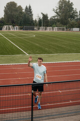 Runner at the stadium. A man takes part in a running competition. Male runner waving to his family