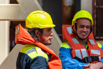 Crew members wear life jackets as they gather for an abandon ship drill, reviewing lifeboat...