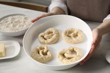 Woman with uncooked pretzels at table in kitchen, closeup