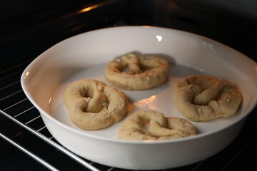 Baking dish with uncooked pretzels in oven, closeup