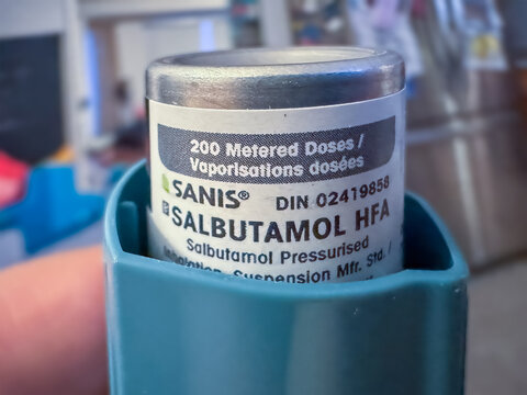 Calgary, Alberta, Canada. Apr 29, 2025. Close-up of a Sanis Salbutamol HFA inhaler canister showing the label with dosage information and DIN number. It's partially inserted into a teal actuator.