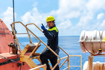Merchant ship crewman, dressed in blue coveralls and a yellow helmet, performing routine duties...
