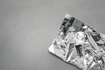 Crumpled piece of aluminum foil on grey background, top view. Space for text