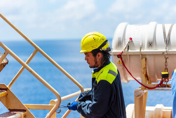 Merchant ship crewman, dressed in blue coveralls and a yellow helmet, performing routine duties...