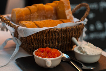 Rustic bread basket with freshly sliced baguette served with tomato and cream dips