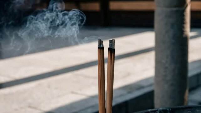 burning joss sticks swaying gently in a calm breeze.
