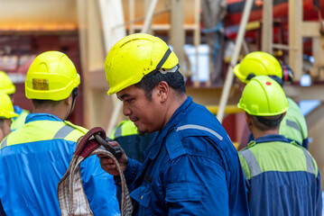 Crew members in blue coveralls and yellow helmets during a safety drill on a merchant ship - real...