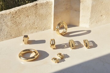 Gold jewelry collection featuring rings and earrings  Various styles of rings and earrings in gold tone, including textured bands,  chunky hoops, and delicate studs,  