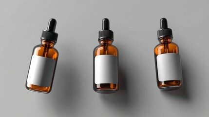 Three amber dropper bottles with blank white labels are arranged on a gray surface.