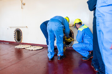 Crew member wearing breathing apparatus exits a narrow hatch after providing first aid during a man...