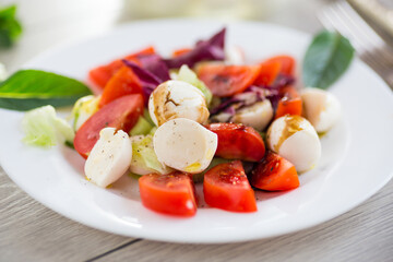 Salad with mozzarella and tomatoes on a wooden table