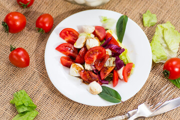 Classic Italian caprese salad for dinner, on a dark rustic table