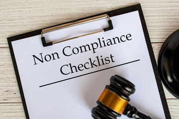 Top view of Non Compliance Checklist text on clipboard with gavel on top. Compliance concept