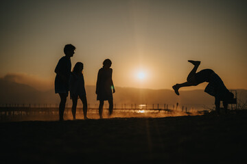 Friends sharing a joyful moment by the beach, silhouetted against a beautiful sunset.