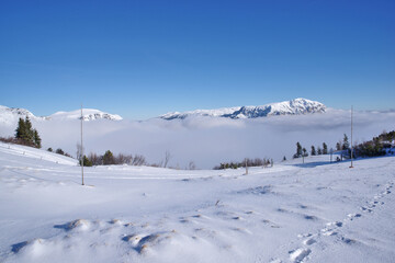 Snowcapped mountain Schneealpe, winter ski tour resort in Styria, Austria. Great view to mountain summit Rax above the fog under deep blue sky.