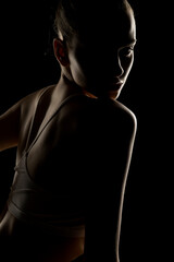 Mysterious side profile of a woman in low-key lighting. Shadows obscure most features, highlighting...