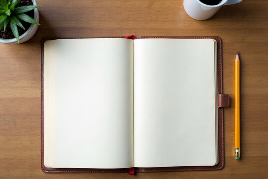 Overhead shot of a blank notebook and a pencil on a wooden desk with space for text.