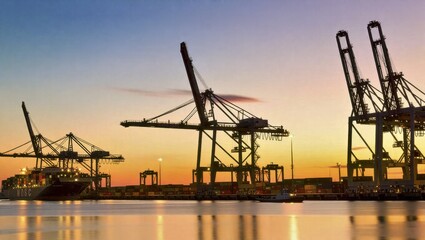 Obraz premium Cargo cranes loading containers at busy port during twilight