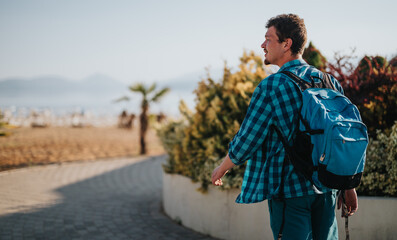A lone traveler explores a sunny beach side walkway, carrying a blue backpack and enjoying the...